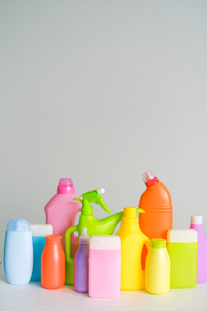 services-02 Assorted colorful plastic cleaning bottles on a white background.